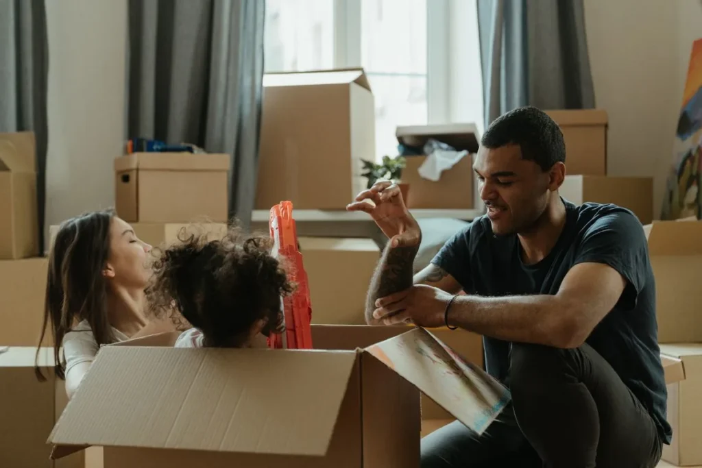 Smiling couple and children playing in a moving box after relocating to their new Melbourne home