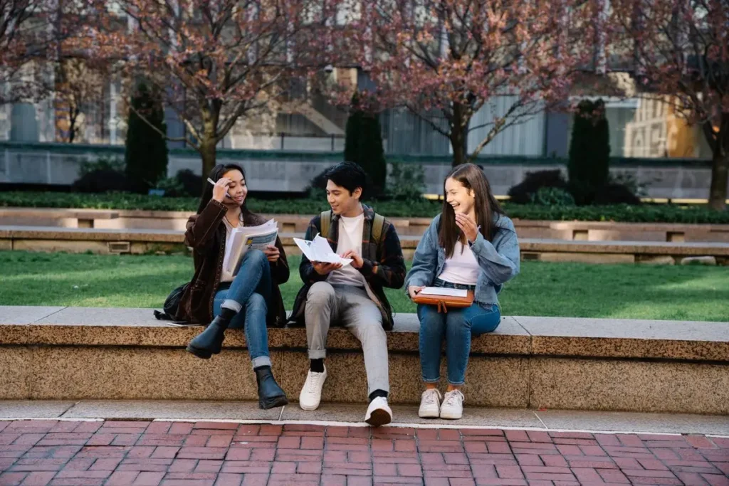 Students sitting outside a Melbourne university with bags and books, preparing for the semester after relocating